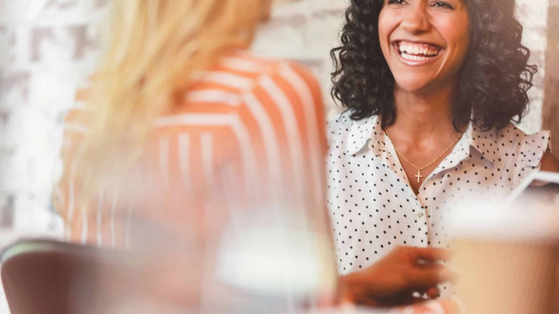 Une femme souriante, naturelle et à l’aise dans une conversation avec une autre personne.