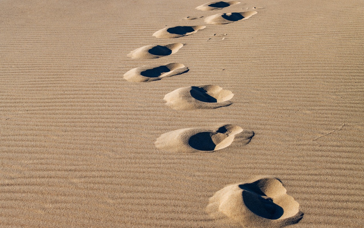Empreintes dans le sable illustrant un chemin d’évolution et de changement en hypnothérapie
